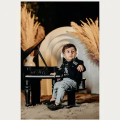 A little rockstar in the making. This cool dude is posing by his mini grand piano in a stylish studio setup with boho pampas grass.