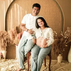 A beautiful portrait of a couple in a casual, boho-inspired studio setting. The mom-to-be's exposed bump and jeans create a modern and authentic look.