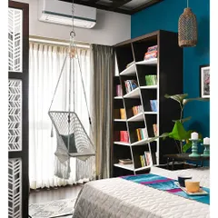 We love creating personal nooks that tell a story. This cozy reading corner features a custom-built asymmetrical bookshelf, a comfortable macrame swing chair, and a vibrant teal accent wall, making it the perfect weekend retreat within your own home.