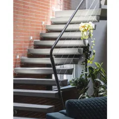 This view shows the entire flight of the floating concrete staircase against a warm brick wall, showcasing the contrast of materials and the elegance of the structure.