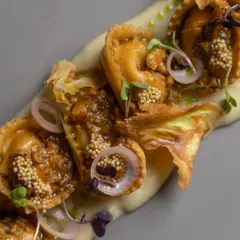 Here, handmade corn and ricotta tortellini are the star. They are served on a bed of parsnip puree and finished with burnt scallion, a hint of chili butter, and pickled mustard for a beautiful interplay of sweet and smoky flavors.