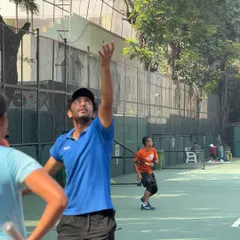 Perfecting the serve toss is crucial. A player works on his service motion during a drill, focusing on consistency and placement under a coach's supervision.