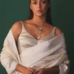 A portrait highlighting a magnificent carved gemstone necklace. I styled it with a simple, elegant off-white ensemble against a deep green background to ensure the unique, heritage-inspired neckpiece remained the focal point.