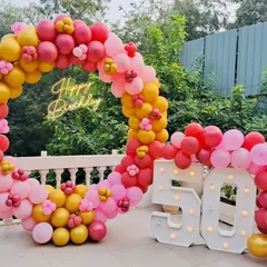 A vibrant and cheerful 50th birthday celebration. This outdoor setup features a massive circular balloon arch in shades of pink, red, and yellow, a "Happy Birthday" neon sign, and large "50" marquee numbers, creating a perfect, joyful photo opportunity.
