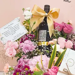 This birthday hamper is the perfect gift from a best friend. It features a bottle of fine wine surrounded by a lush arrangement of pink and purple flowers, along with a personalized birthday card and other curated goodies.