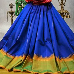 A magnificent royal blue Kanjivaram silk saree with a unique temple border in green and gold. The striking color combination and pure zari work make this a standout piece for any grand event.