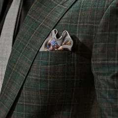 A close-up on the details of the green checked suit. The texture of the fabric, the subtle pattern, and the perfectly chosen pocket square all contribute to its refined character.