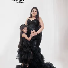 A beautiful moment between a mother and her daughter, both dressed in matching black gowns. It's so special to include older siblings in the maternity shoot to celebrate the growing family.