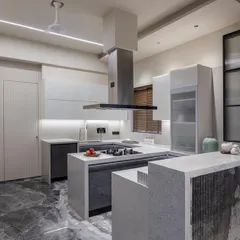 A full view of the U-shaped kitchen layout, featuring a multi-level island that serves as both a prep area and a breakfast bar. The mix of white glass cabinets and dark ceramic finishes creates a balanced, modern look.