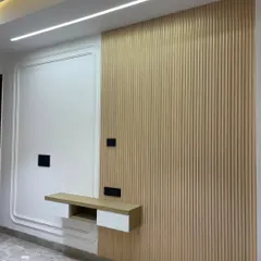 This cozy wall design is perfect for a TV unit. It features a combination of white molded paneling and light wood fluting, with a floating shelf that is both stylish and practical.