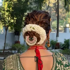 A close-up of the bridal bun, showing the intricate detail of the fresh flower gajra and hair accessory.