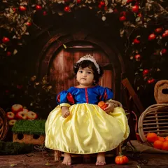 Another regal pose from our little Snow White, sitting patiently in her fairytale scene surrounded by apples and rustic props.
