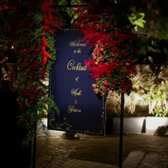 The welcome sign for a grand cocktail night, framed by lush red florals. This entrance sets a dramatic and luxurious tone, promising guests an evening of royal treatment.