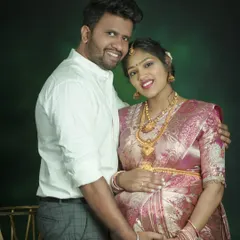A classic studio portrait of a couple in traditional wear. Their happy smiles and close embrace radiate warmth and joy, perfectly celebrating their journey to parenthood.