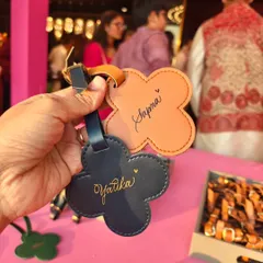 Holding up two personalized luggage tags at a Mehendi event. Each name is written by hand, offering guests a truly unique and personal party favor.