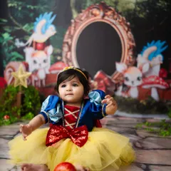 A perfect portrait of a sitting Snow White, holding a bright red apple. The details in her costume and the magical forest backdrop make this photo truly special.