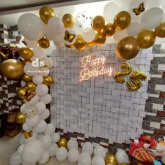A glamorous white and gold theme for a 25th birthday celebration at home. This decor features a balloon half-arch, a 'Happy Birthday' neon sign, and foil balloons for the age.
