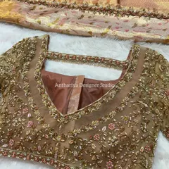 A beautiful beige blouse with a sheer, embroidered overlay. The design features a modern square neckline and delicate floral embroidery, perfect for a sophisticated and contemporary look.