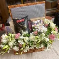 I love incorporating fresh flowers into my hampers to add a touch of natural beauty. This wicker basket is filled with white and pink blooms, gourmet truffle chips, and other gift boxes.