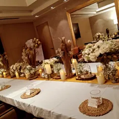 An elegant table setting for a small gathering. The white and gold theme features beautiful floral centerpieces, candles, and birdcage accents for a sophisticated look.