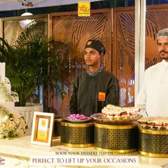 Book your dessert haven to lift up your occasions. A beautiful three-tiered wedding cake is the centerpiece of this elegant dessert station.
