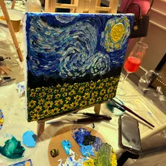 A perfect evening combines art and good company. Here's a finished Van Gogh-inspired masterpiece from a sip and paint session, complete with a palette of rich, textured colors and a celebratory drink.