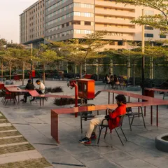 The Red Ribbon Plaza in use. The design encourages various forms of social interaction, from individual work to group conversations. It activates the outdoor space of the campus, fostering a sense of community and well-being among employees.