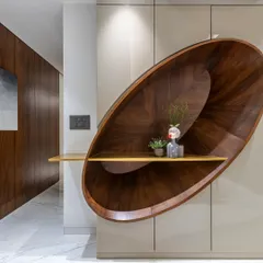 A close-up of the sculptural wooden shelving unit in the Filigree House. The curved form and rich grain of the wood make this functional piece a true work of art.
