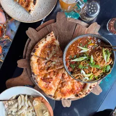 A perfect flat lay showcasing a delicious spread at a trendy Noida cafe. I focus on making the food look as good as it tastes, capturing everything from wood-fired pizza and savory noodles to creamy pasta, encouraging my audience to save the spot for their next meal.