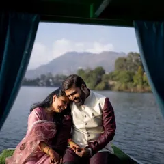 A candid and joyful moment of a couple on a boat in Nainital, with the mountains and water creating a picturesque and romantic setting.