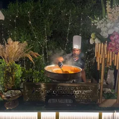 A chef prepares a large batch of Mutton Nalli Burra at a live cooking station. The rising steam and rich aroma of this traditional Mughlai dish create an immersive and memorable experience for guests.
