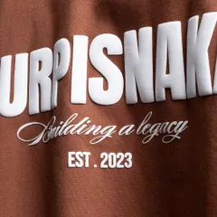 A super close-up shot of the "Purpisnake" t-shirt, focusing on the high-quality, raised texture of the puff-print graphic.