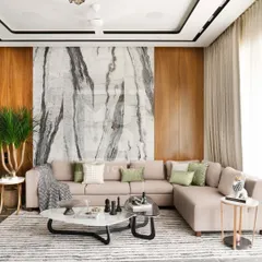 This living room design features a neutral L-shaped sofa set against a striking marble and wood-paneled wall. The striped area rug and layered coffee tables add texture and interest, creating a space that is both calm and sophisticated.