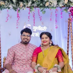 The happy couple poses for a classic portrait on a decorated jhula, or swing, a centerpiece of the Dohale Jevan ceremony. The floral arch and festive backdrop create a perfect setting for this memorable baby shower photograph.