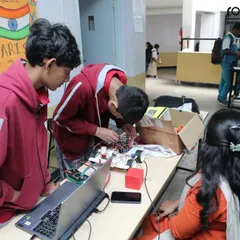 Teamwork in action. Students collaborate on a complex wiring task for their robot, learning to solve problems together and share ideas. This is a vital skill for any future engineer or innovator.