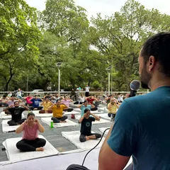 An instructor guides a large group through Bhramari Pranayama (humming bee breath) during an outdoor community event in Chandigarh.