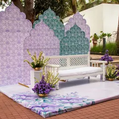 A minimal yet striking Moroccan-inspired Mehendi stage. The custom-printed backdrops and flooring, paired with a simple white bench and purple floral accents, create a chic and modern look.
