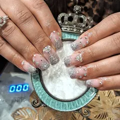 "Glass slipper" style nails featuring a sheer base with silver glitter and crystal accents, finished with a crown-themed holder.