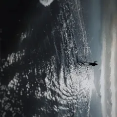 An artistic top down drone shot of a person standing on the shoreline in Goa. The contrast between the dark, wet sand, the white foam of the waves, and the lone figure creates a powerful and contemplative image.