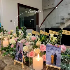 A close-up of the 50th-anniversary tablescape. We used mini photo easels displaying the couple's memories alongside pillar candles and delicate arrangements of roses and eucalyptus.