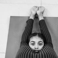 Yoga is a journey of connecting with the self. This powerful image of a young girl in a deep forward bend shows the focus and introspection that can be found even at a young age.