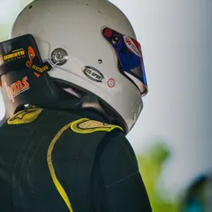 A close-up of a driver's helmet and HANS device, essential safety equipment for high-speed formula racing.