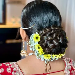 A beautiful and intricate braided bun, decorated with a mix of fresh yellow and white flowers. This hairstyle is a work of art in itself.