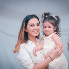 A mother holding her daughter, both smiling for the camera. Our family portraits aim to be natural and reflect the genuine happiness you share.