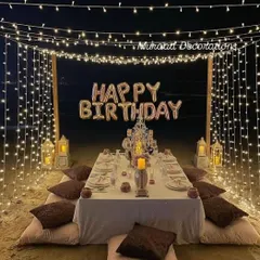 A romantic dinner setup on a beach or terrace. We created a canopy of fairy lights over a beautifully set low dining table with floor cushions, perfect for a memorable birthday evening.