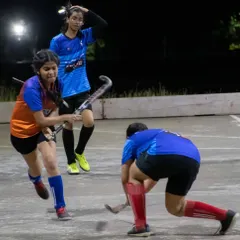 A player executes a reverse-stick shot under pressure from a defender. We teach advanced skills to all our players, ensuring they have a complete technical toolkit.
