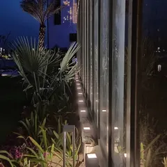 A close-up view of the ground-level lighting for the Zirakpur office. In-ground uplights are used to wash the vertical fins with light, creating a rhythmic pattern and highlighting the adjacent landscaping.