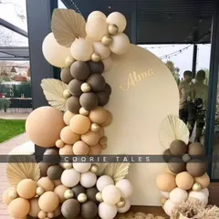 A beautiful example of our minimalist boho aesthetic. This outdoor setup uses a simple arched backdrop and a tastefully arranged balloon garland in neutral tones, accented with dried palm leaves for a touch of texture.