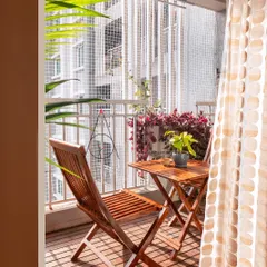 A view from inside looking out onto the transformed balcony. The wooden deck and chairs create a warm, inviting space that encourages you to step outside and enjoy your private green corner.
