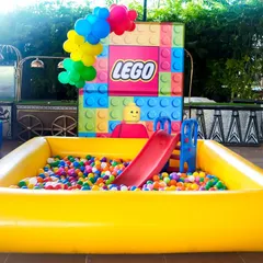 A large, inflatable ball pit with a slide, perfect for younger guests at this LEGO-themed party.